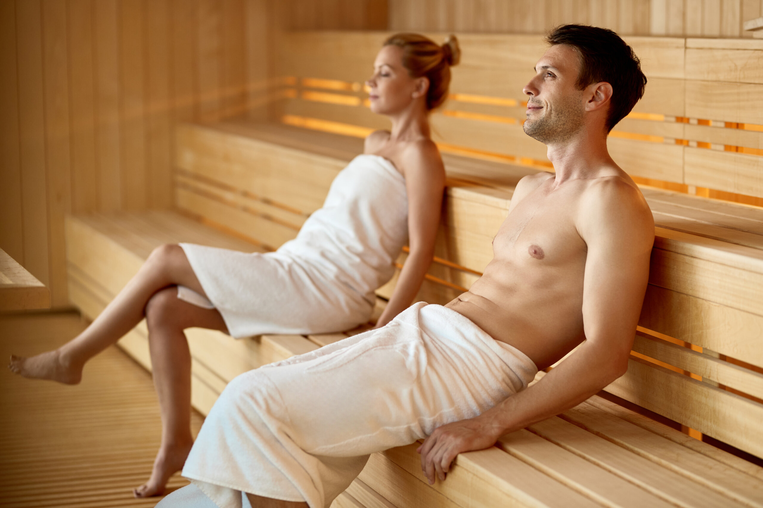 Smiling man day dreaming while relaxing in sauna at the spa.